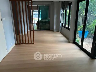 Spacious living room with wooden flooring and large windows overlooking garden