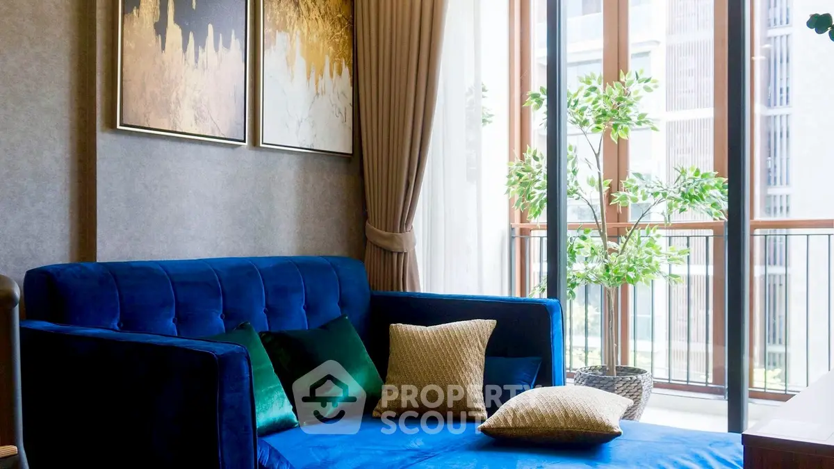 Elegant living room with blue sofa and large windows opening to a balcony.