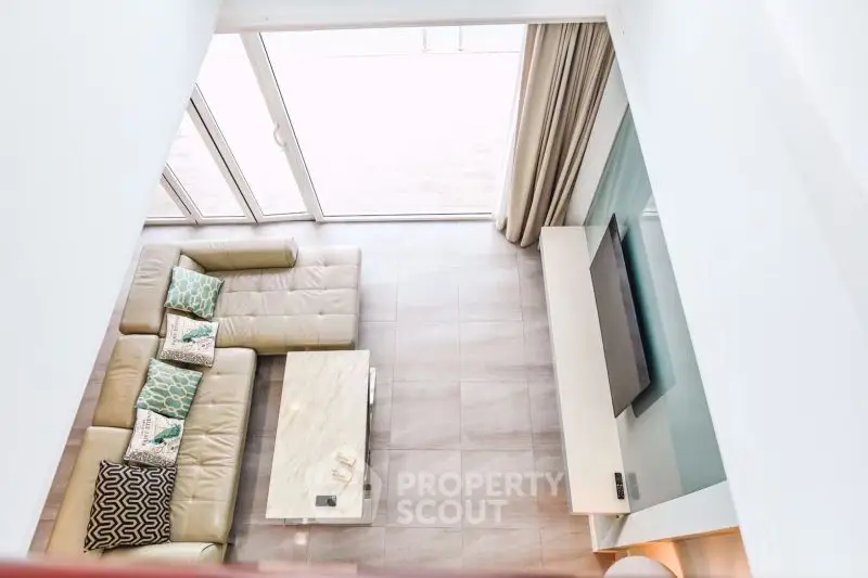 Spacious modern living room with large sofa and flat-screen TV, perfect for relaxation.