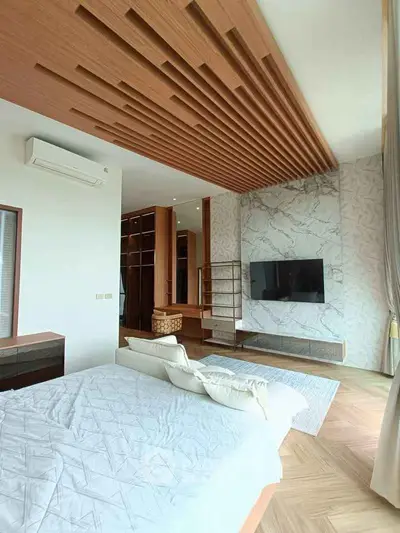 Luxurious bedroom with modern design, featuring a stylish ceiling, wall-mounted TV, and elegant decor.