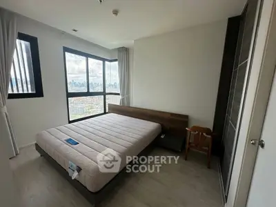 Spacious bedroom with city view, featuring a large window and modern furnishings.