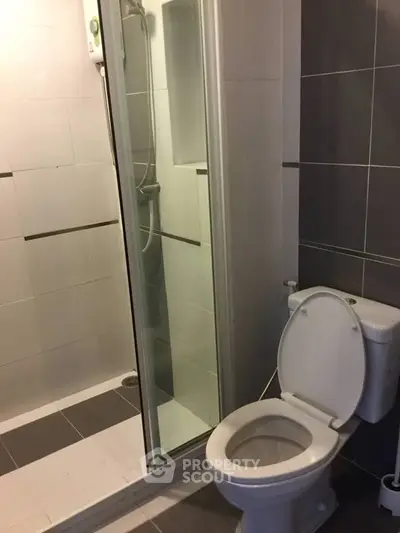 Modern bathroom with shower and toilet in sleek tile design.