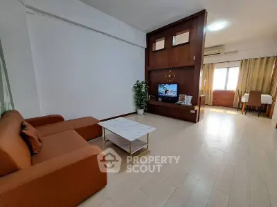 Spacious living room with modern decor and natural light, featuring a cozy sofa and entertainment center.