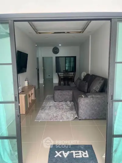Modern living room with sleek gray sofa and wall-mounted TV, perfect for relaxation and entertainment.