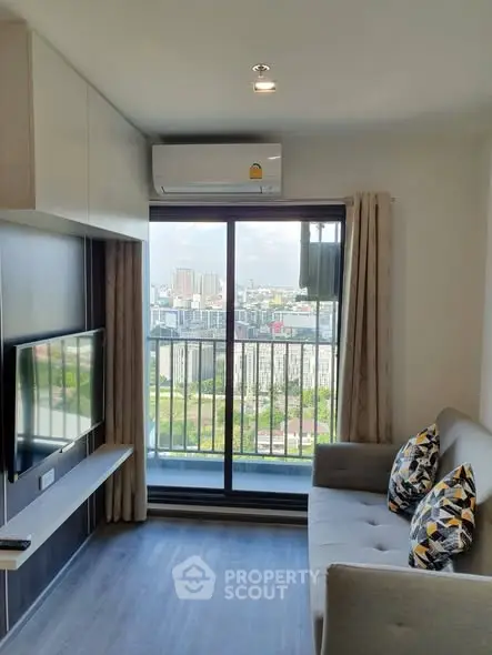 Modern living room with city view, featuring a sleek sofa and wall-mounted TV.