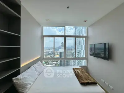 Modern bedroom with stunning city view and wall-mounted TV in high-rise apartment.