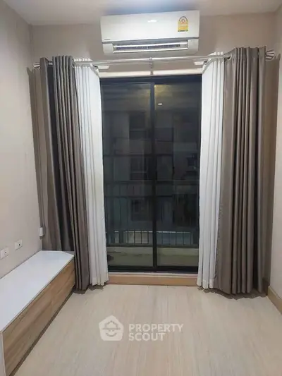 Modern room with large window and air conditioning, featuring elegant curtains and wooden flooring.