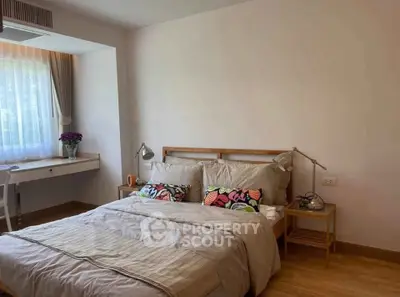 Cozy bedroom with natural light, stylish decor, and wooden flooring for a serene living experience.