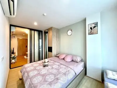 Modern bedroom with stylish decor and ample natural light, featuring a cozy bed and sleek storage solutions.