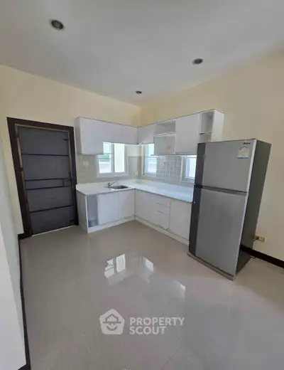 Modern kitchen with sleek cabinets and stainless steel fridge in a bright apartment.