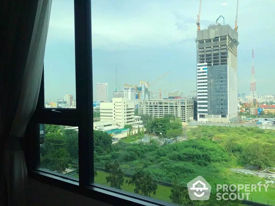 Stunning cityscape view from a high-rise window showcasing urban development and greenery.