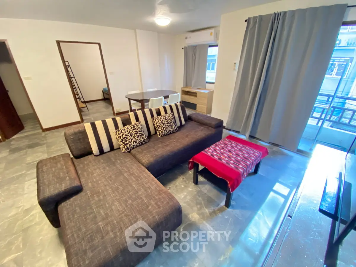 Spacious living room with modern sofa and dining area in a bright apartment.
