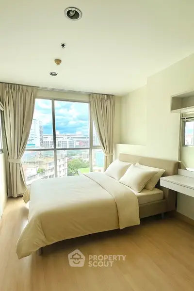 Bright bedroom with large window offering city view, modern furnishings, and neutral decor.