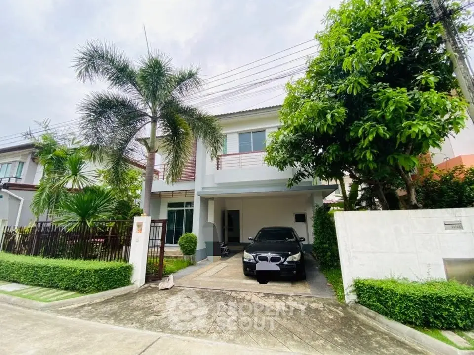 Charming two-story house with driveway and lush greenery in a serene neighborhood.