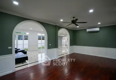 Spacious living room with elegant arches and hardwood floors in a modern home.