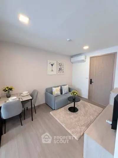 Modern living room with cozy seating and dining area, featuring stylish decor and bright lighting.