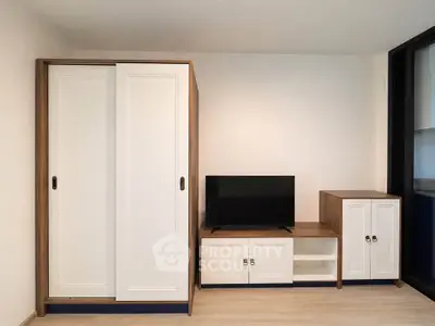 Modern living room with sleek white cabinets and a flat-screen TV on wooden furniture.