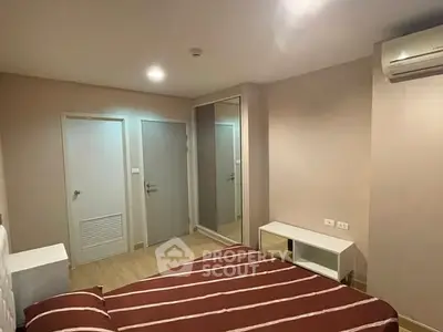 Modern bedroom with striped bedding, mirrored closet, and air conditioning in a cozy apartment.