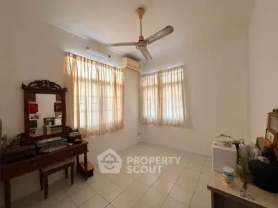 Charming vintage bedroom with natural light, classic furniture, and ceiling fan, perfect for cozy living.