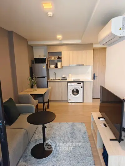 Modern studio apartment with open kitchen and cozy living area, featuring a washing machine and stylish decor.