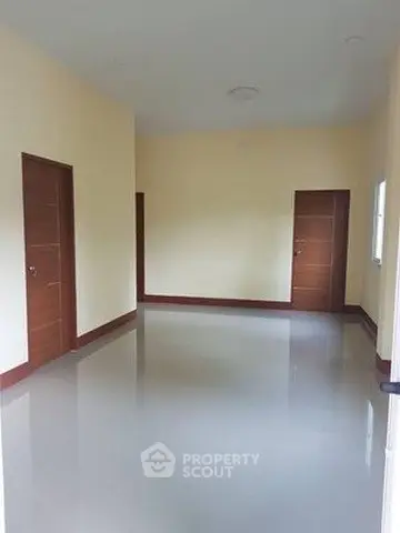 Spacious empty room with glossy flooring and wooden doors, ideal for customization.