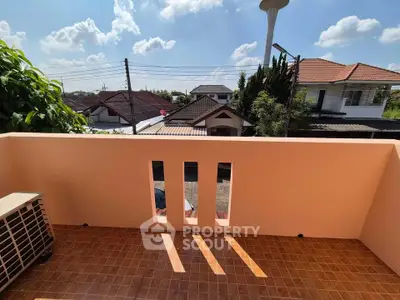 Charming balcony with terracotta tiles and scenic neighborhood view under a clear blue sky.