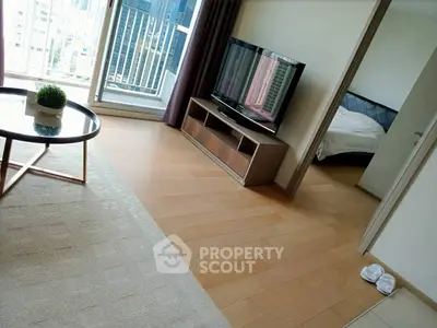 Modern living room with TV and balcony view, adjacent to a cozy bedroom.