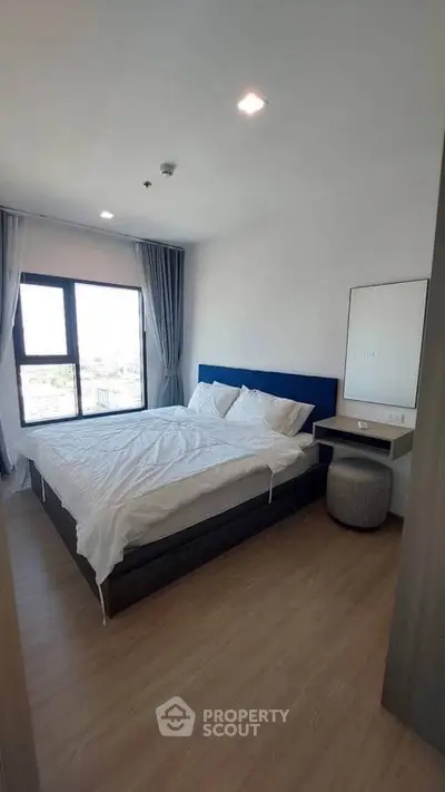 Modern bedroom with large window and stylish decor in a contemporary apartment.
