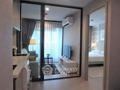 Modern apartment interior with open living room and bedroom, featuring sleek furniture and natural light.