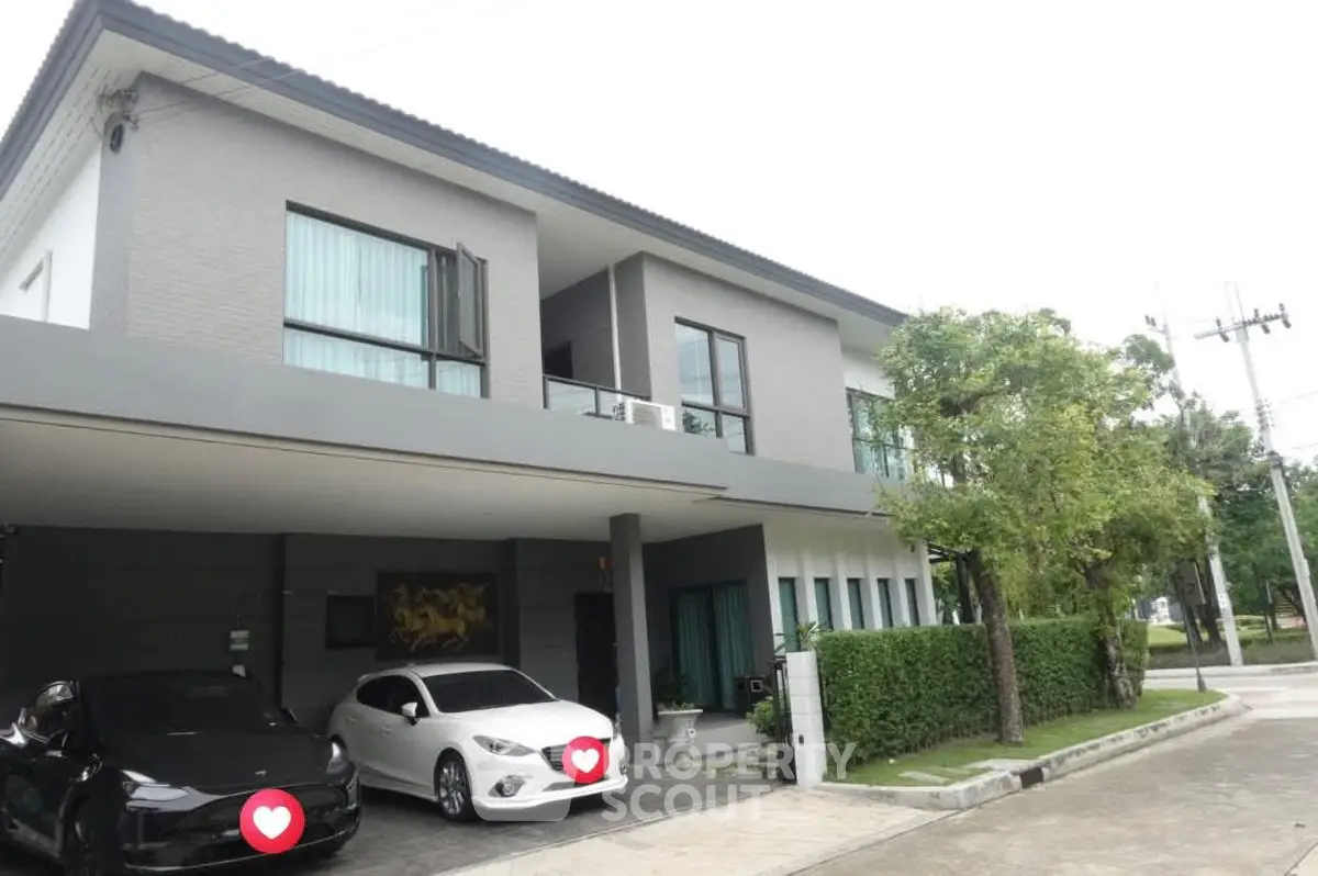 Modern two-story house with carport and lush greenery in a serene neighborhood.
