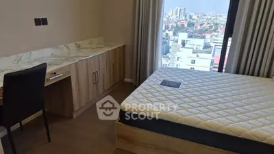 Modern bedroom with city view, featuring a sleek desk and comfortable bed.