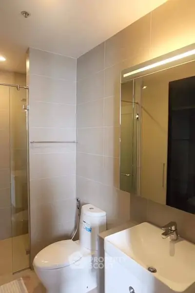 Modern bathroom with sleek fixtures and glass shower enclosure in a contemporary apartment.