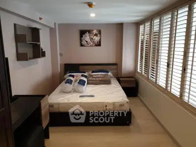 Cozy bedroom with modern decor and ample natural light from large windows.