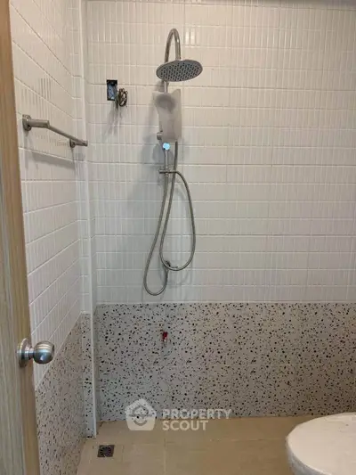 Modern bathroom with sleek showerhead and tiled walls, perfect for contemporary living.