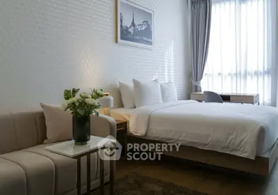 Elegant bedroom with modern decor, featuring a cozy bed, stylish sofa, and natural light from large windows.