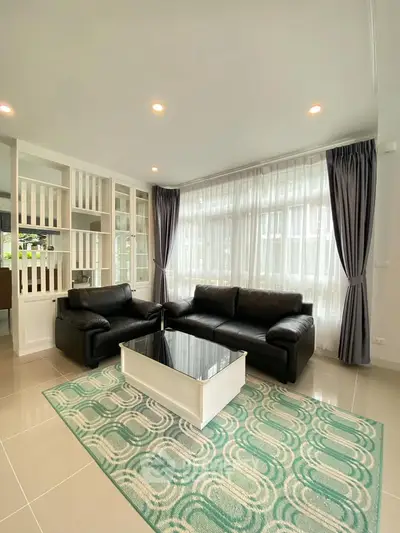 Modern living room with sleek black sofas and large windows