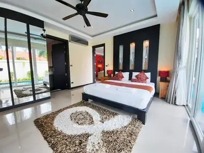 Luxurious bedroom with modern decor, large windows, and stylish ceiling fan in a serene setting.