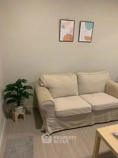 Cozy living room with beige sofa, modern art, and indoor plant for a welcoming ambiance.