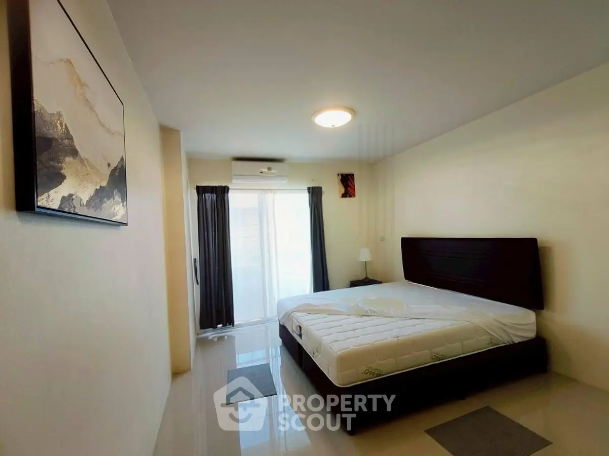 Spacious bedroom with modern decor and natural light from large window.