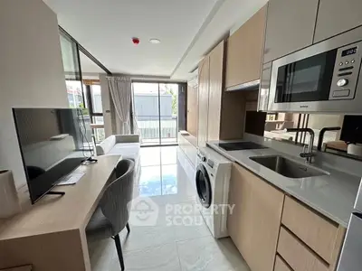 Modern apartment kitchen with sleek appliances and open layout, featuring a washing machine and microwave.