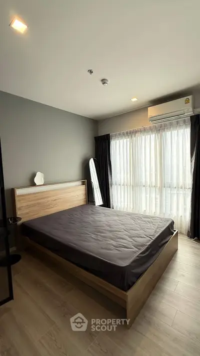 Spacious bedroom with modern decor and large window for natural light