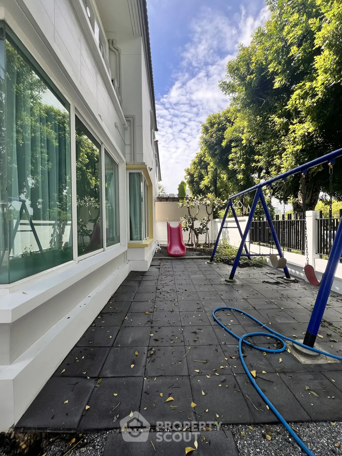 Charming outdoor patio with playground swing set and lush greenery, perfect for family relaxation and play.