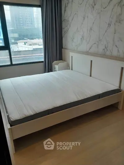 Modern bedroom with large window and stylish marble accent wall in urban apartment.