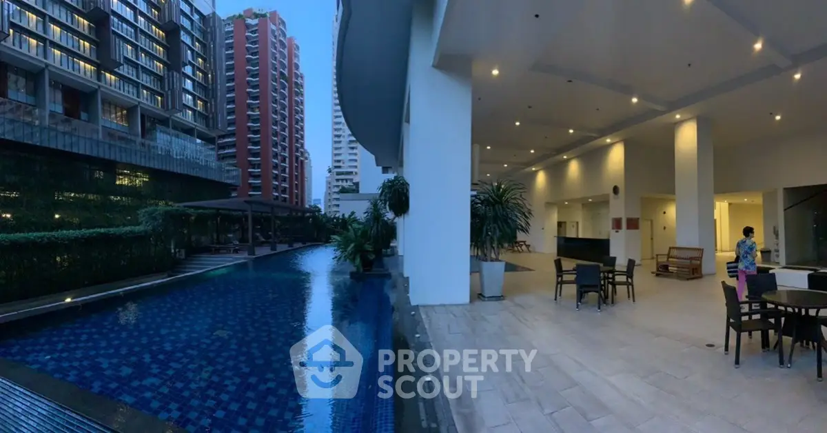 Luxurious condominium with stunning pool and modern outdoor seating area at dusk.