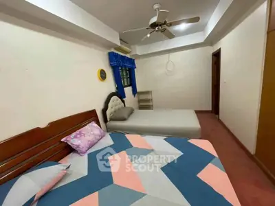 Spacious bedroom with two beds and ceiling fan, ideal for comfort and relaxation.