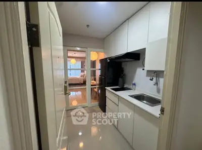 Modern kitchen with sleek cabinetry and open layout leading to a cozy living area.