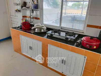 Modern kitchen with gas stove and ample storage, featuring bright orange and white cabinetry.