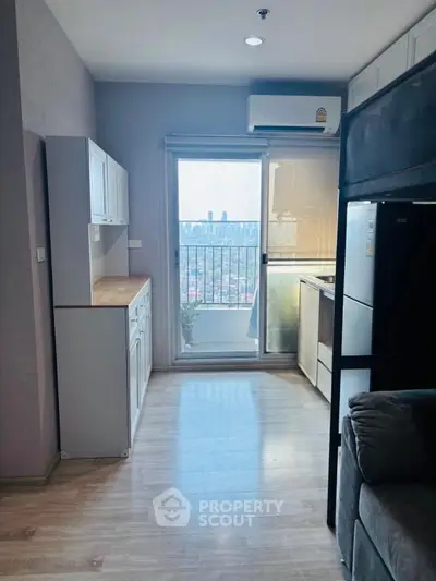 Modern apartment with balcony and city view, featuring sleek kitchen and cozy living area.
