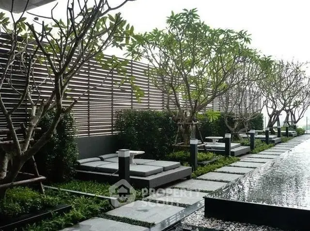 Luxurious rooftop garden with modern lounge chairs and water feature, perfect for relaxation and leisure.