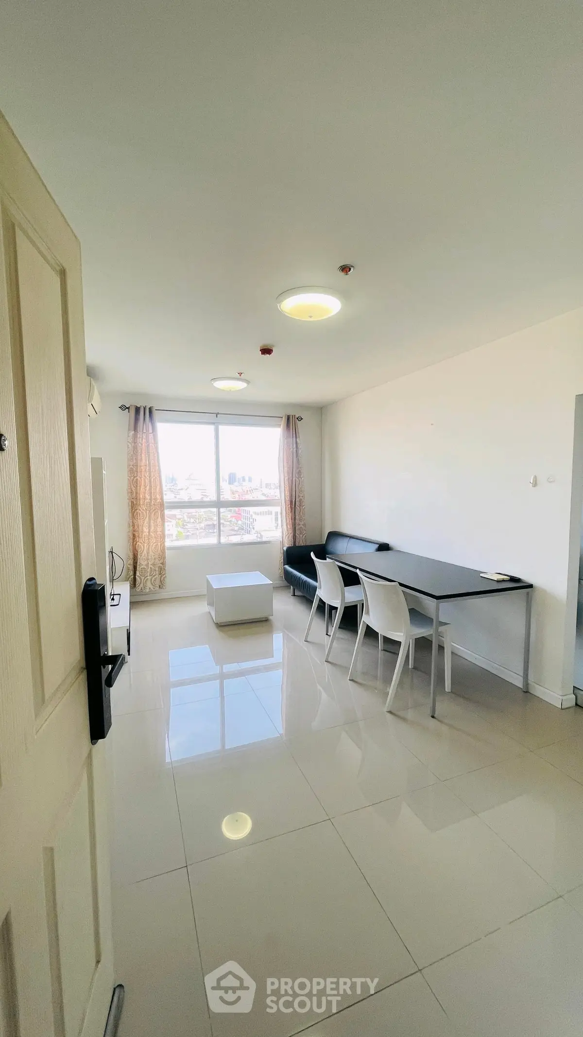 Spacious modern living room with sleek furniture and large window offering city views.